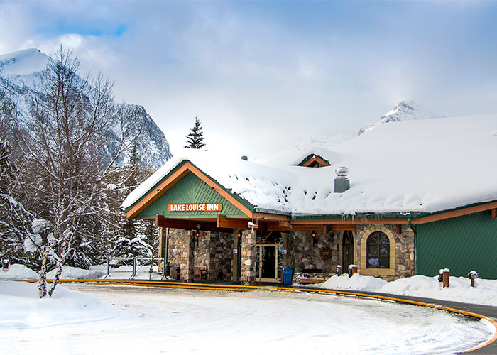 Snow covered entrance of the Lake Louise Inn surrounded my mountains